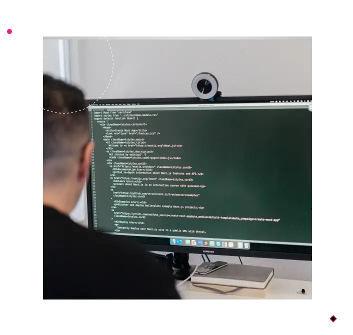Developer coding on a large desktop screen showing software code in a modern workspace