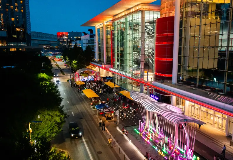 Nighttime view of the Houston convention center with people dining and colorful lights.
