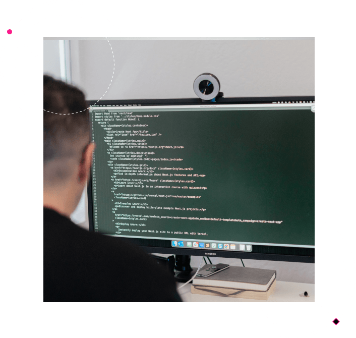 Developer coding on a large desktop screen showing software code in a modern workspace