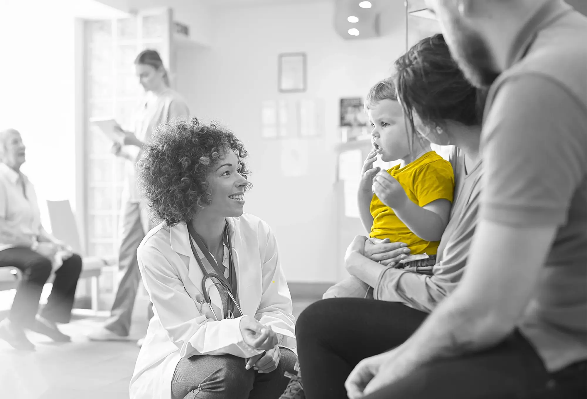 Doctor smiling and talking to a child in a clinic waiting room.