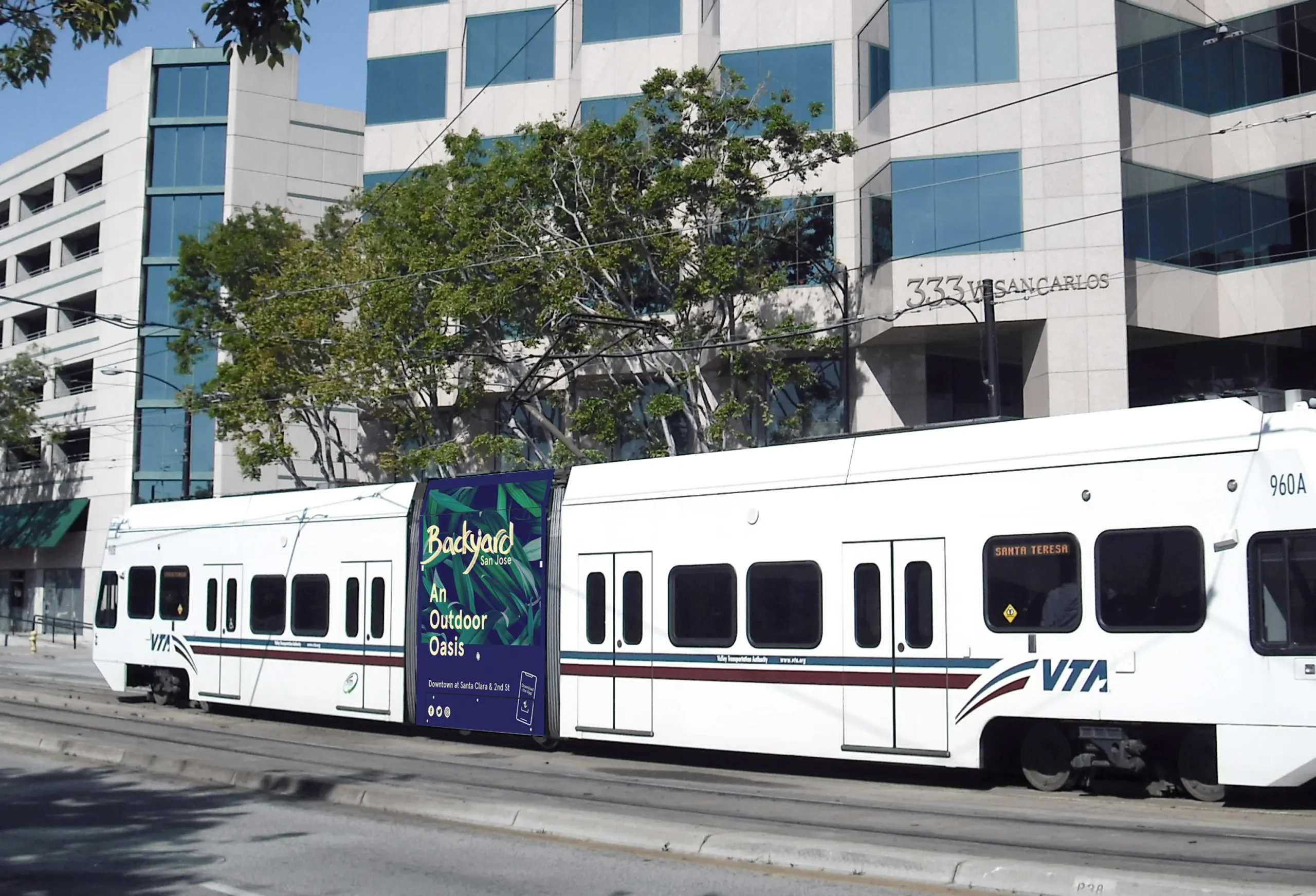 Light rail train in downtown San Jose displaying a Backyard San Jose outdoor oasis advertisement on the side panel, promoting the community space
